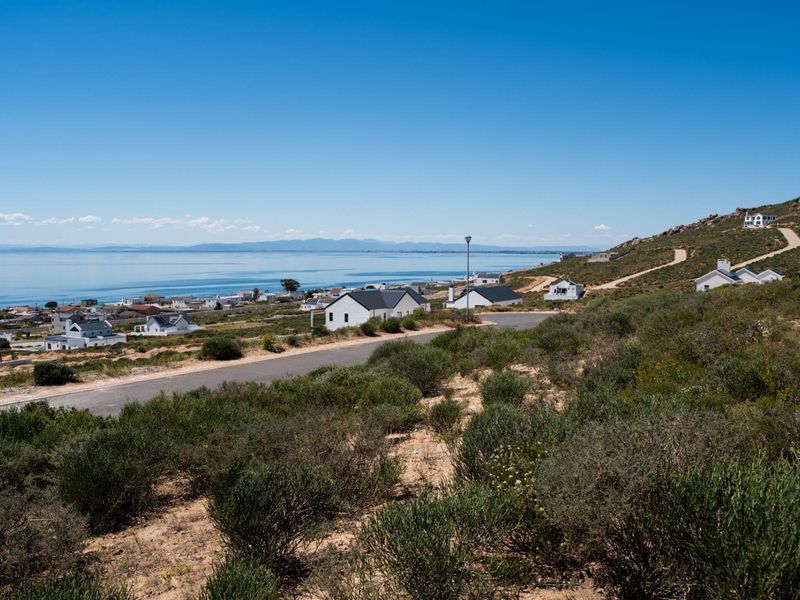 A scenic elevated view overlooking a coastal residential area with paved roads and distant ocean vistas.