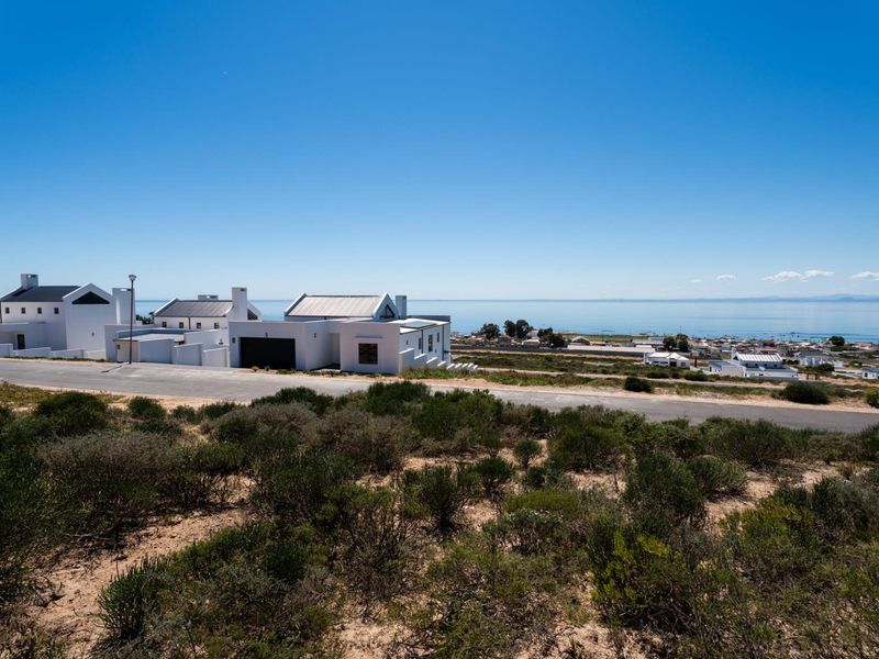 A scenic elevated view overlooking a coastal residential area with modern homes and a clear horizon line over the ocean.