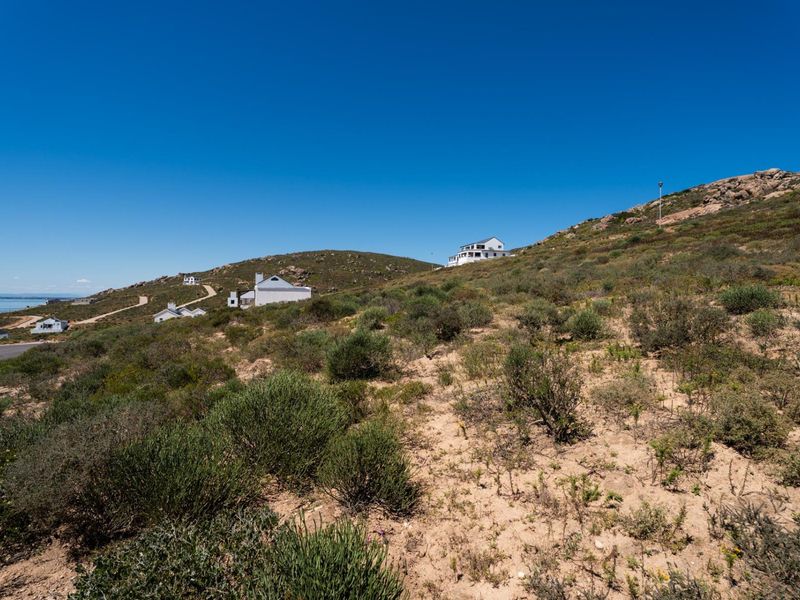 A scenic view of the coastal landscape and surrounding residential properties, showcasing the natural terrain and open space of the vacant land.
