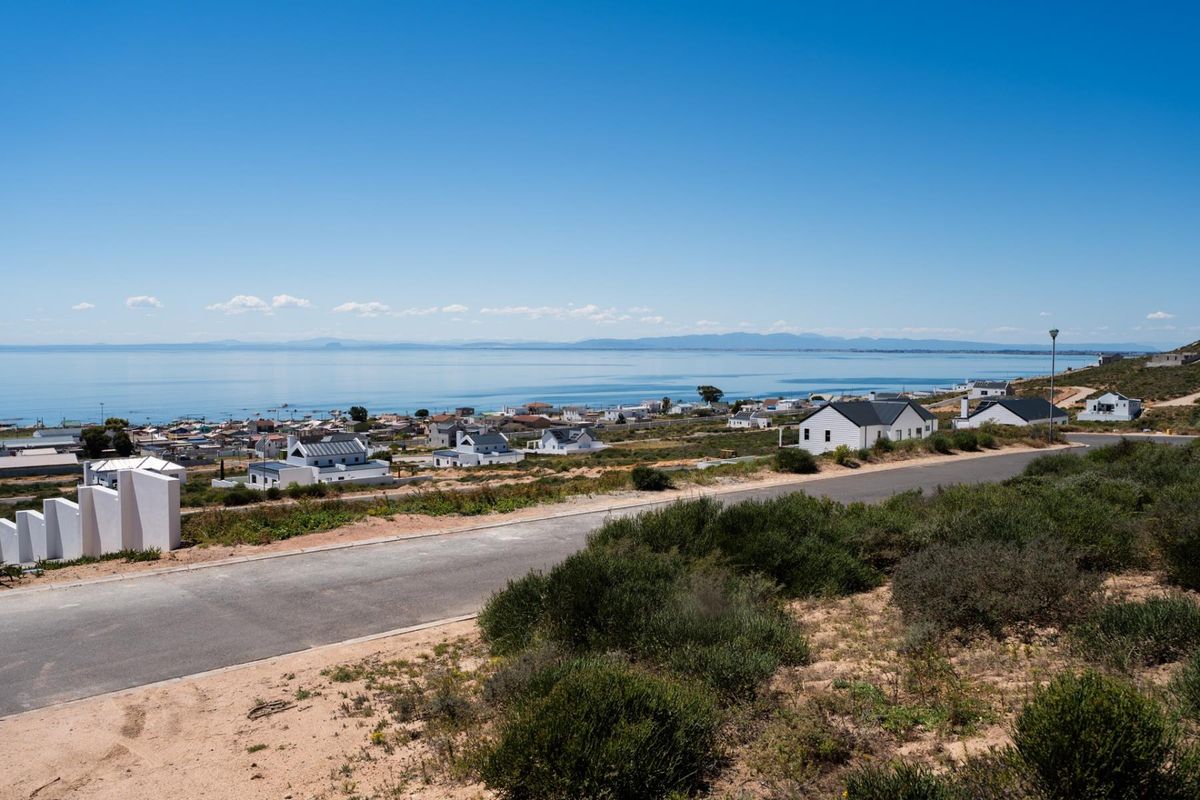 Elevated view overlooking a coastal residential area with a clear sea horizon and surrounding natural landscape.