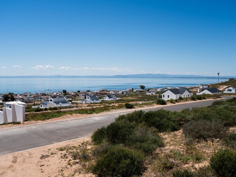 Elevated view overlooking a coastal residential area with a clear sea horizon and surrounding natural landscape.