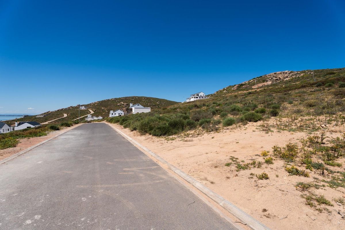 A view of the paved street and concrete curbing bordering the vacant residential land in a coastal hillside development.