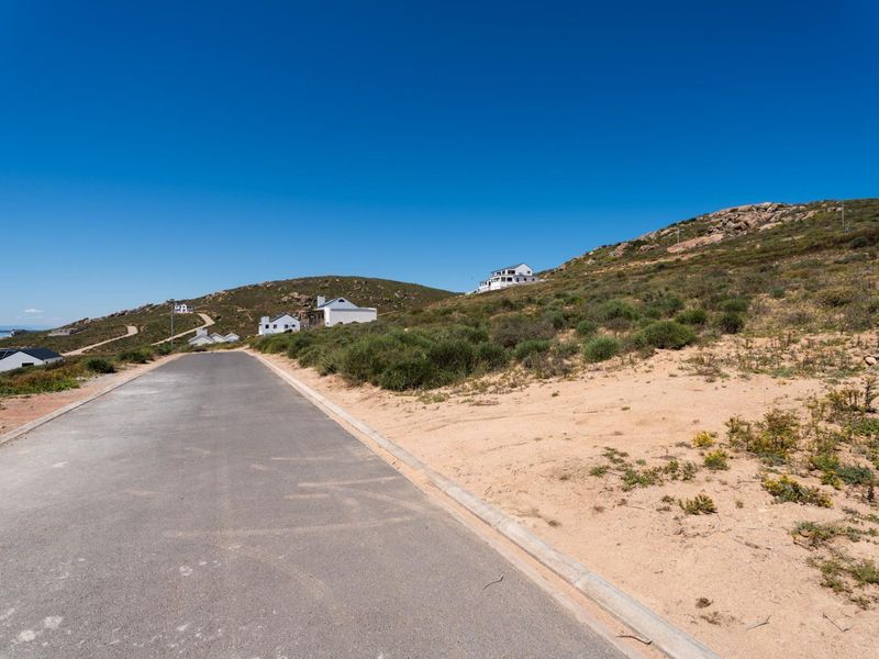 A view of the paved street and concrete curbing bordering the vacant residential land in a coastal hillside development.