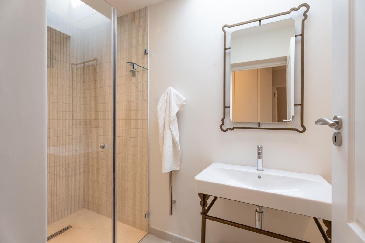 Modern bathroom featuring a walk-in shower with glass screen, wall-mounted basin, and a skylight providing natural light.