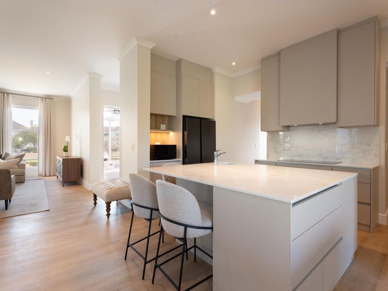 Modern open-plan kitchen featuring a central island with stone countertops, sleek cabinetry, and high-quality finishes, seamlessly flowing into the adjacent living area.