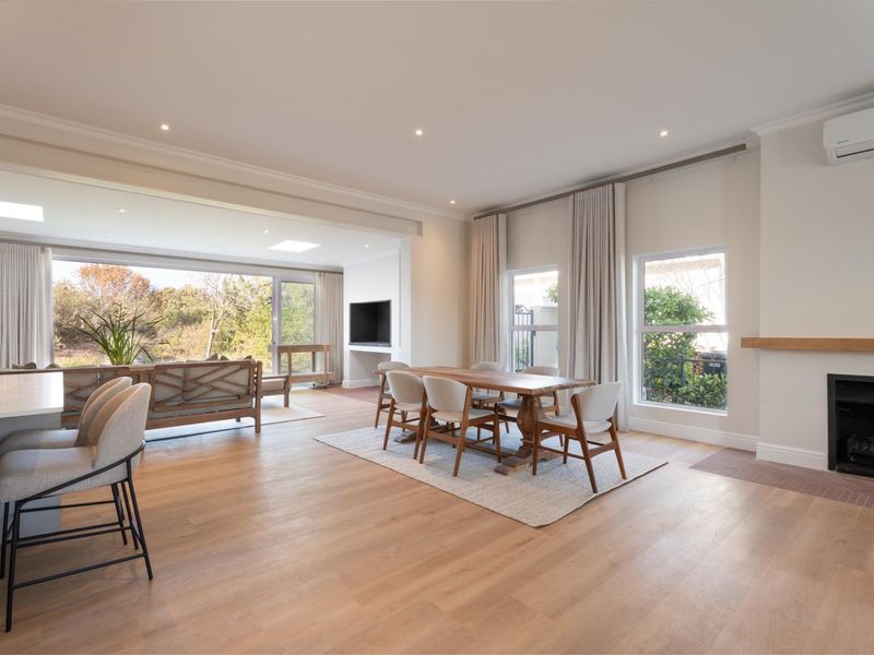 Spacious open-plan living and dining area featuring engineered timber flooring, a built-in fireplace, and large sliding doors providing seamless access to the outdoors.