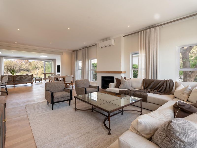 Spacious open-plan living area featuring timber flooring, a built-in fireplace with a timber mantel, and large sliding doors leading to an outdoor space.