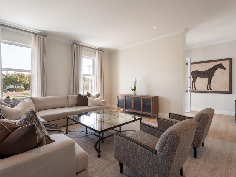 A bright and spacious living room featuring high-quality timber flooring, recessed downlighting, and large windows that provide ample natural light.