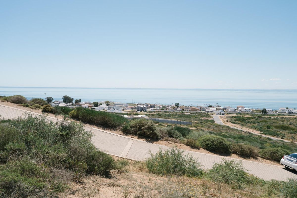 A scenic elevated view overlooking the coastal landscape and nearby residential area, featuring a paved access road in the foreground.