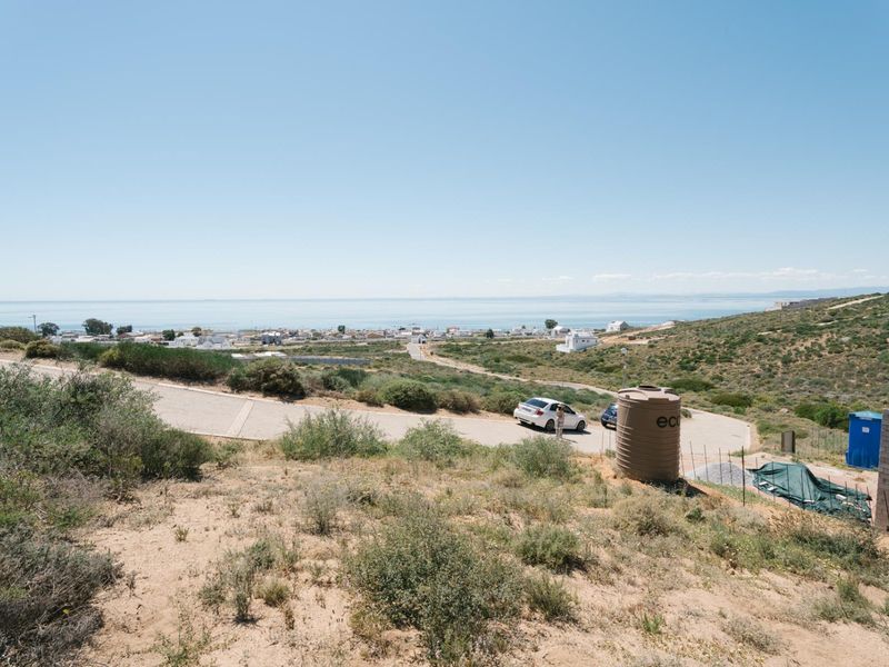 Elevated view of the surrounding landscape, coastal area, and paved access road from the vacant residential plot.