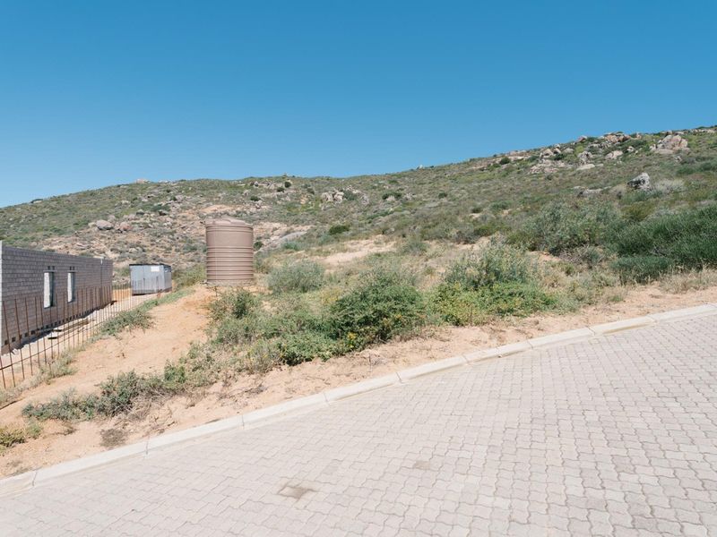 Vacant residential land featuring a paved driveway, a water tank, and the initial concrete block wall construction of a new build.