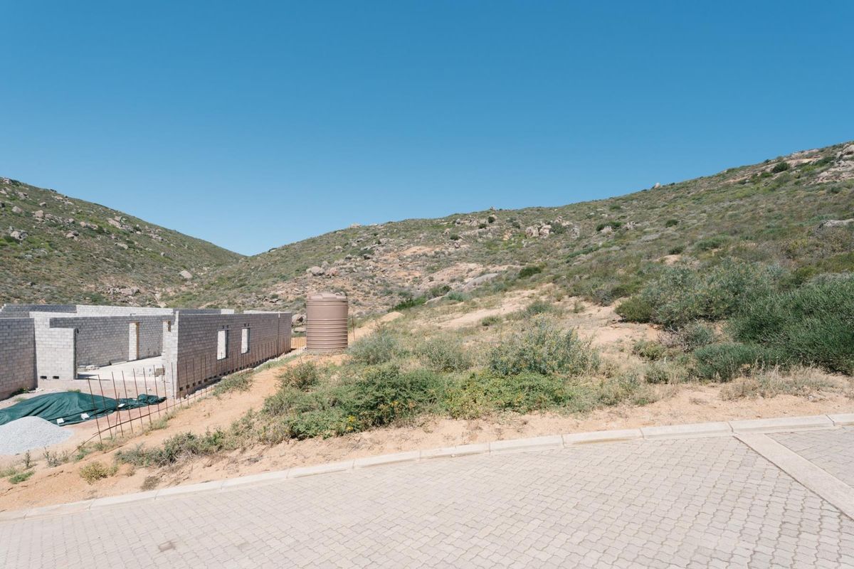 Vacant residential land featuring an ongoing construction project with concrete block walls, a water storage tank, and paved street access.