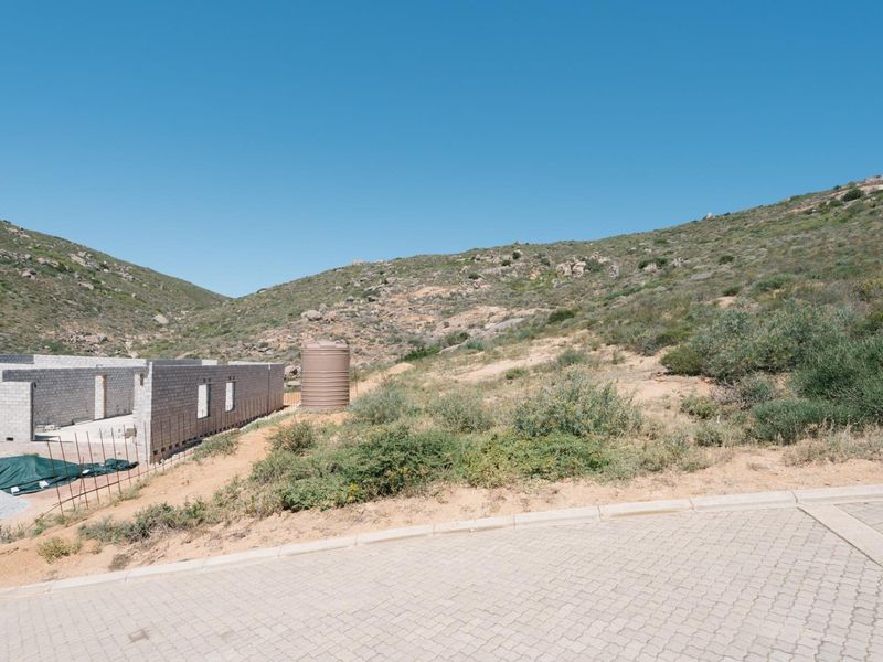 Vacant residential land featuring an ongoing construction project with concrete block walls, a water storage tank, and paved street access.
