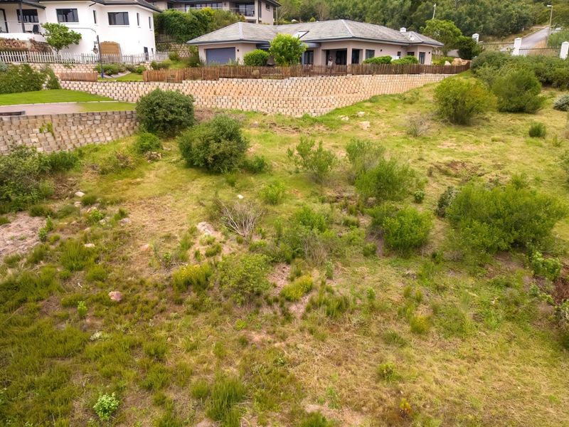 An aerial view of a vacant residential plot featuring established retaining walls and perimeter fencing, situated in a developed neighborhood.