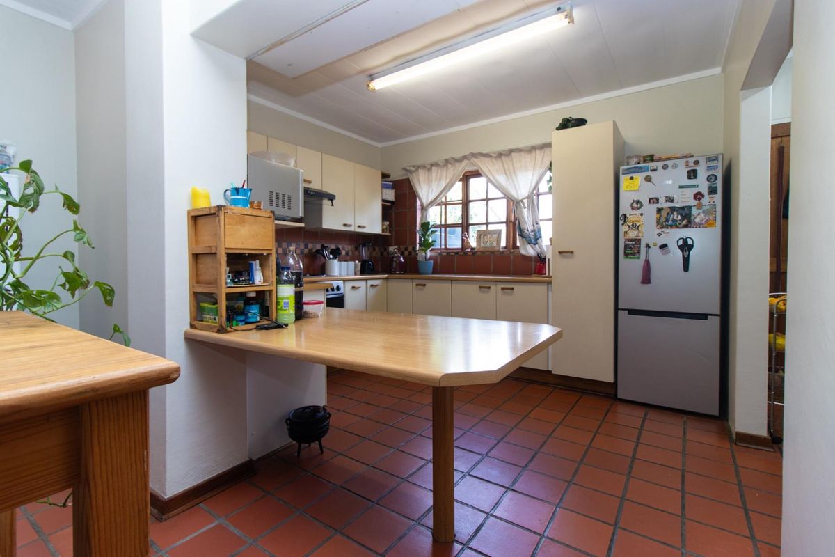 A functional kitchen featuring built-in cabinetry, a tiled backsplash, and a convenient breakfast bar, offering a practical layout with potential for modern updates.