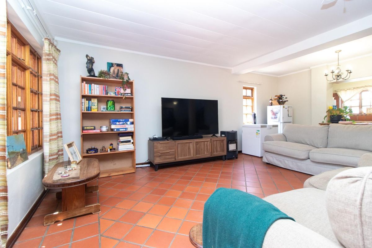 A spacious living room featuring traditional terracotta tile flooring, timber-framed windows, and a classic tongue and groove ceiling, offering a warm and inviting atmosphere.