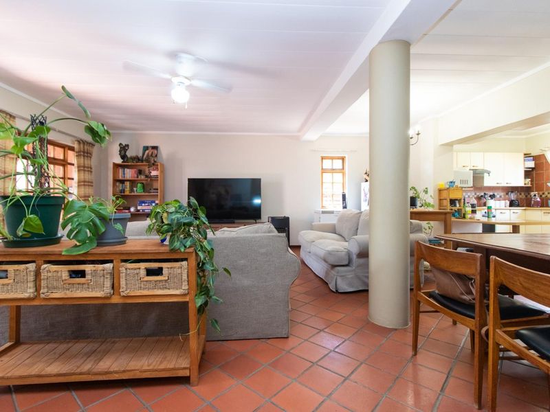 Spacious open-plan living and dining area featuring terracotta floor tiles, a central structural column, and an integrated kitchen with ample cabinetry.