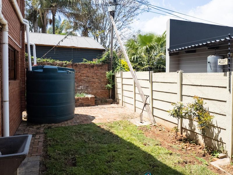 A rear courtyard area featuring a water storage tank, brick paving, and perimeter walling with electric fencing.