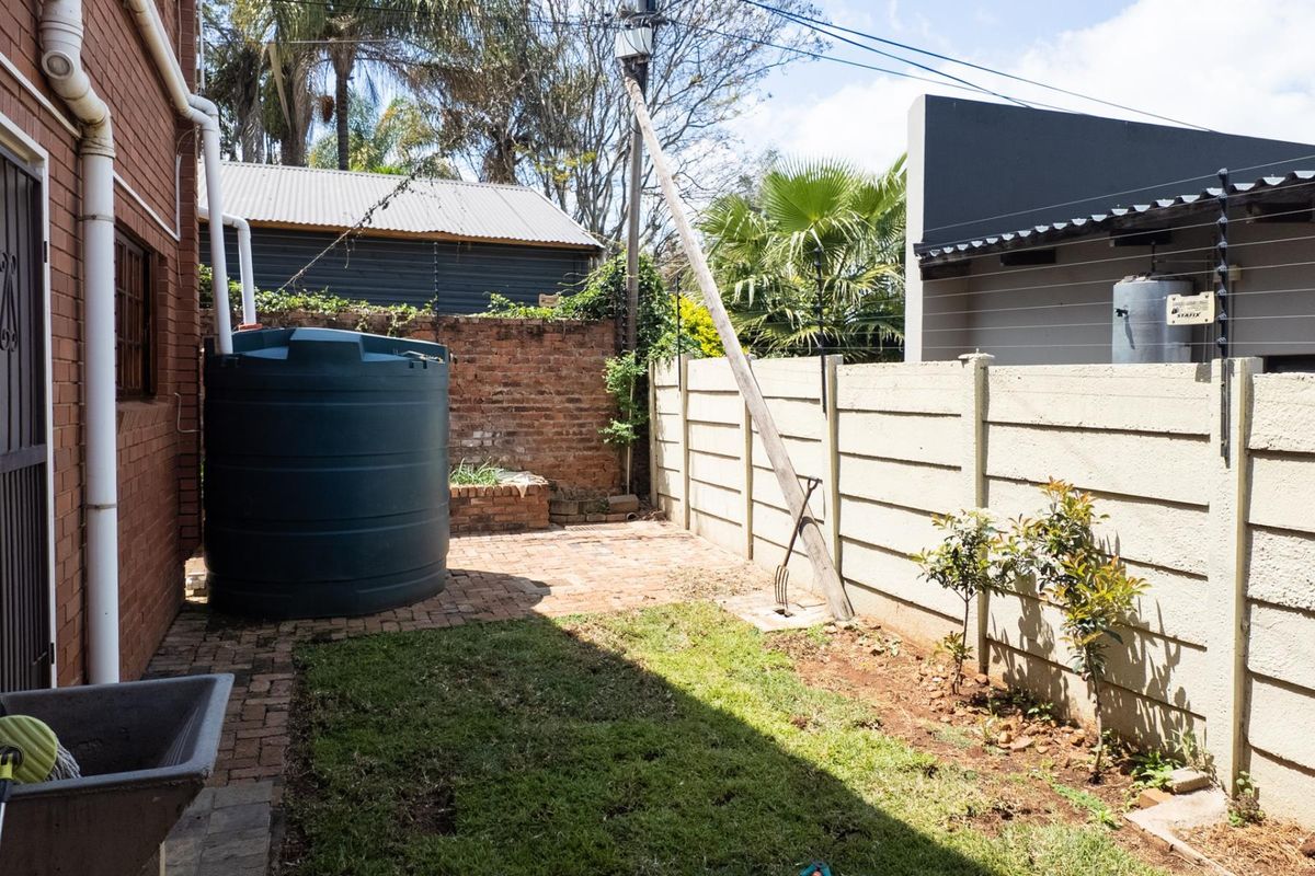 A rear courtyard area featuring a water storage tank, brick paving, and perimeter walling with electric fencing.
