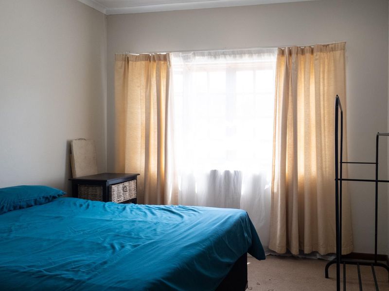 A bedroom featuring carpeted flooring and a window with installed curtain rails, providing natural light to the space.