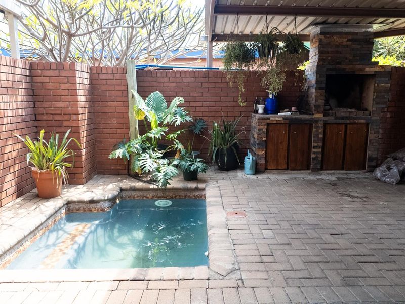 Covered patio area featuring a built-in brick braai and a small plunge pool, enclosed by a private brick boundary wall.
