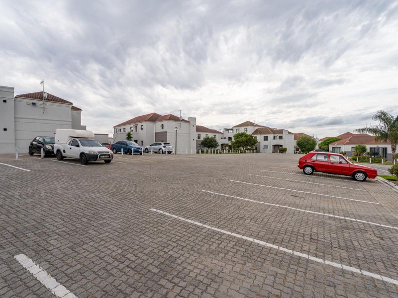 A wide-angle view of the apartment complex parking area featuring paved surfaces and multiple residential building blocks.