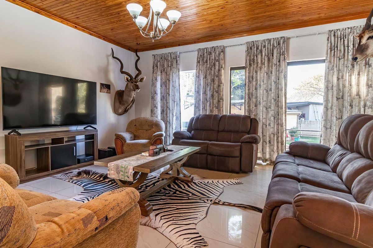 Spacious living room featuring tiled flooring and a warm timber tongue and groove ceiling, with direct access to the outdoor area via sliding doors.
