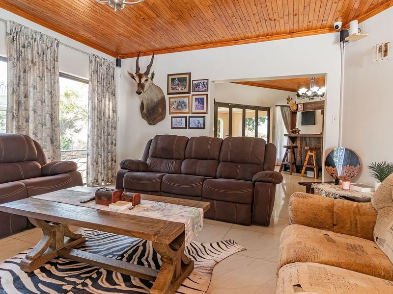 Spacious living room featuring a warm timber tongue and groove ceiling, tiled flooring, and an open transition to an adjacent built-in bar area.