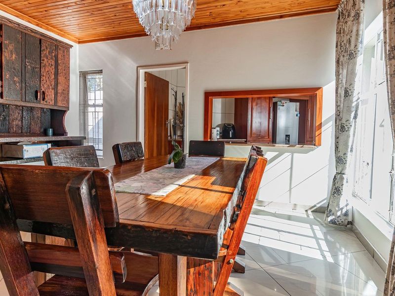 Dining room featuring a timber ceiling, tiled flooring, and built-in wooden cabinetry with a convenient serving hatch connecting to the kitchen area.