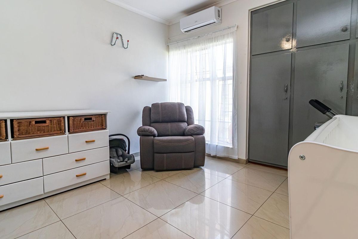 A well-lit bedroom featuring tiled flooring, a built-in wardrobe, and a wall-mounted split-system air conditioner.