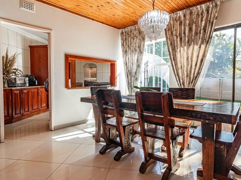 Spacious dining room featuring tiled flooring, a timber ceiling, and a convenient pass-through window connecting to the kitchen area.
