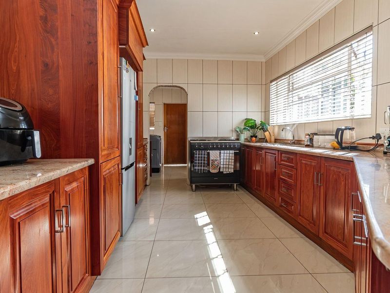 A functional kitchen featuring warm-toned wooden cabinetry, granite countertops, tiled flooring, and a freestanding oven, offering a classic and practical workspace.