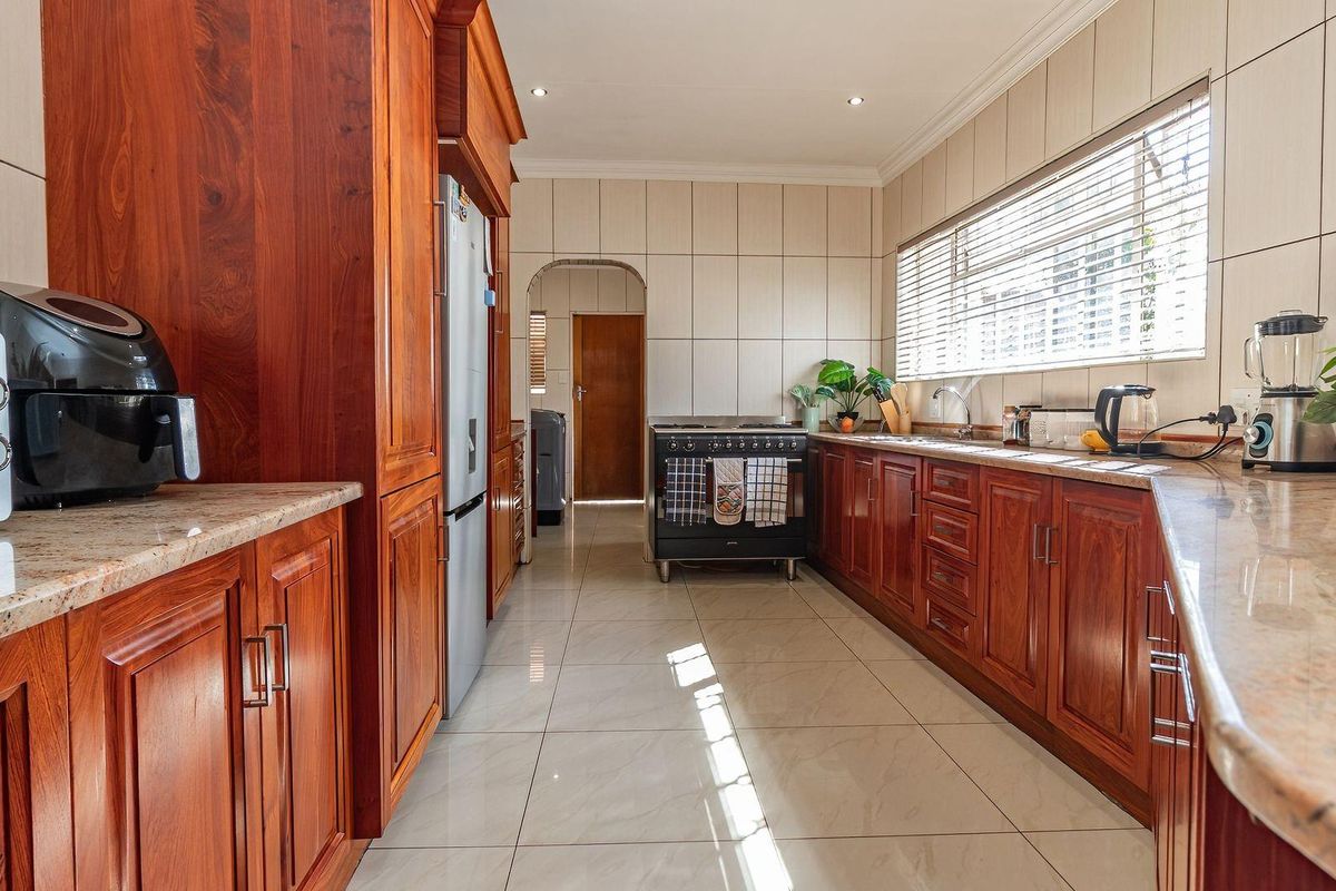 A functional kitchen featuring warm-toned wooden cabinetry, granite countertops, tiled flooring, and a freestanding oven, offering a classic and practical workspace.
