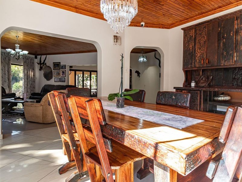 Dining room featuring a timber ceiling, tiled flooring, and built-in wooden cabinetry, connected to the living area through arched doorways.