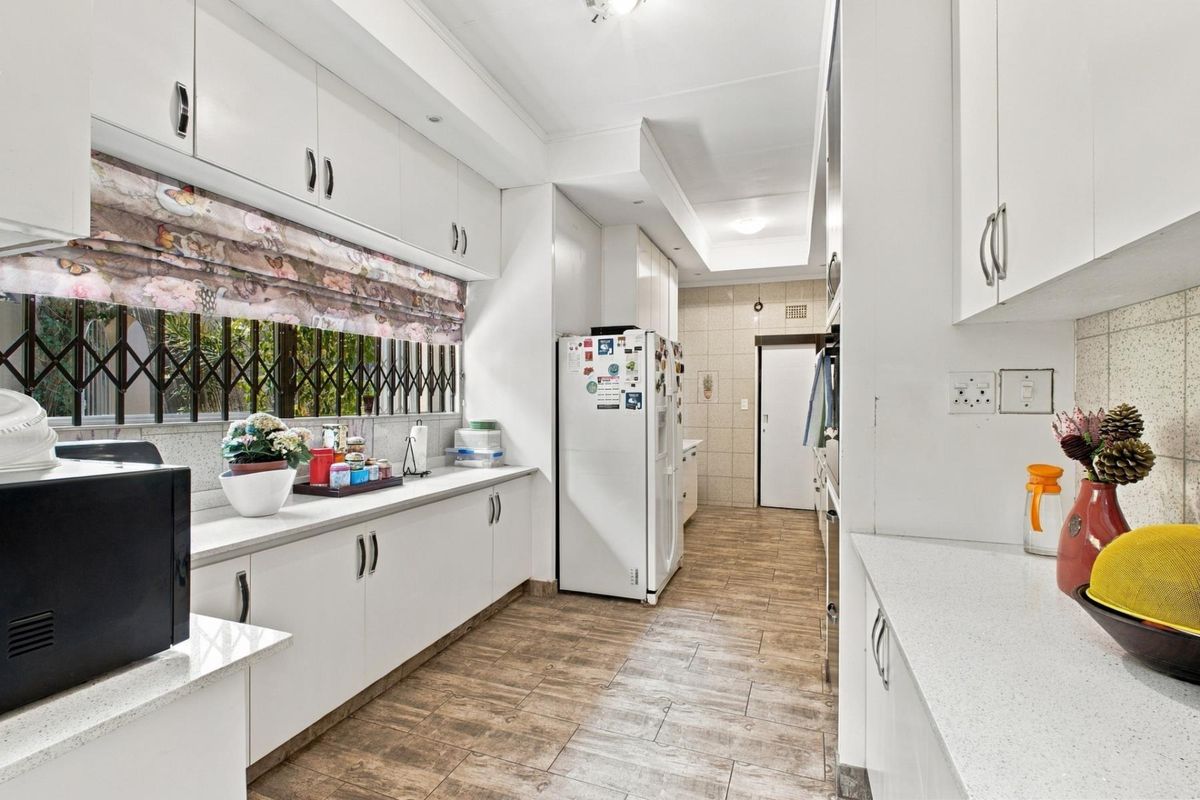 A functional kitchen featuring white cabinetry, stone countertops, tiled flooring, and a tiled backsplash, offering ample storage and workspace.
