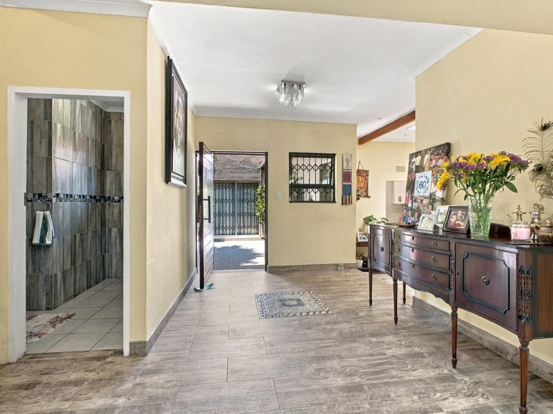 Spacious entrance hall featuring wood-look tiled flooring, neutral walls, and direct access to a tiled shower area and exterior entrance.