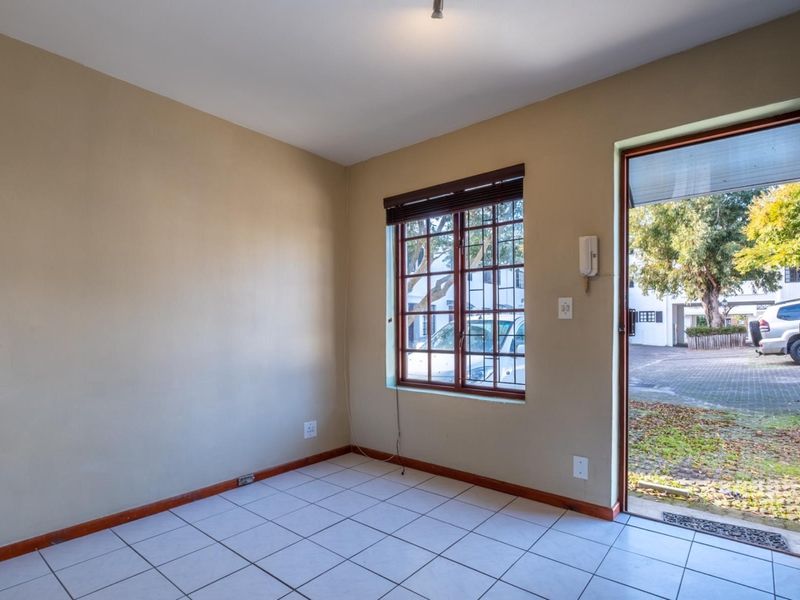 An empty entrance area featuring tiled flooring, a timber window, and a direct exterior door access, providing a functional transition space for the apartment.