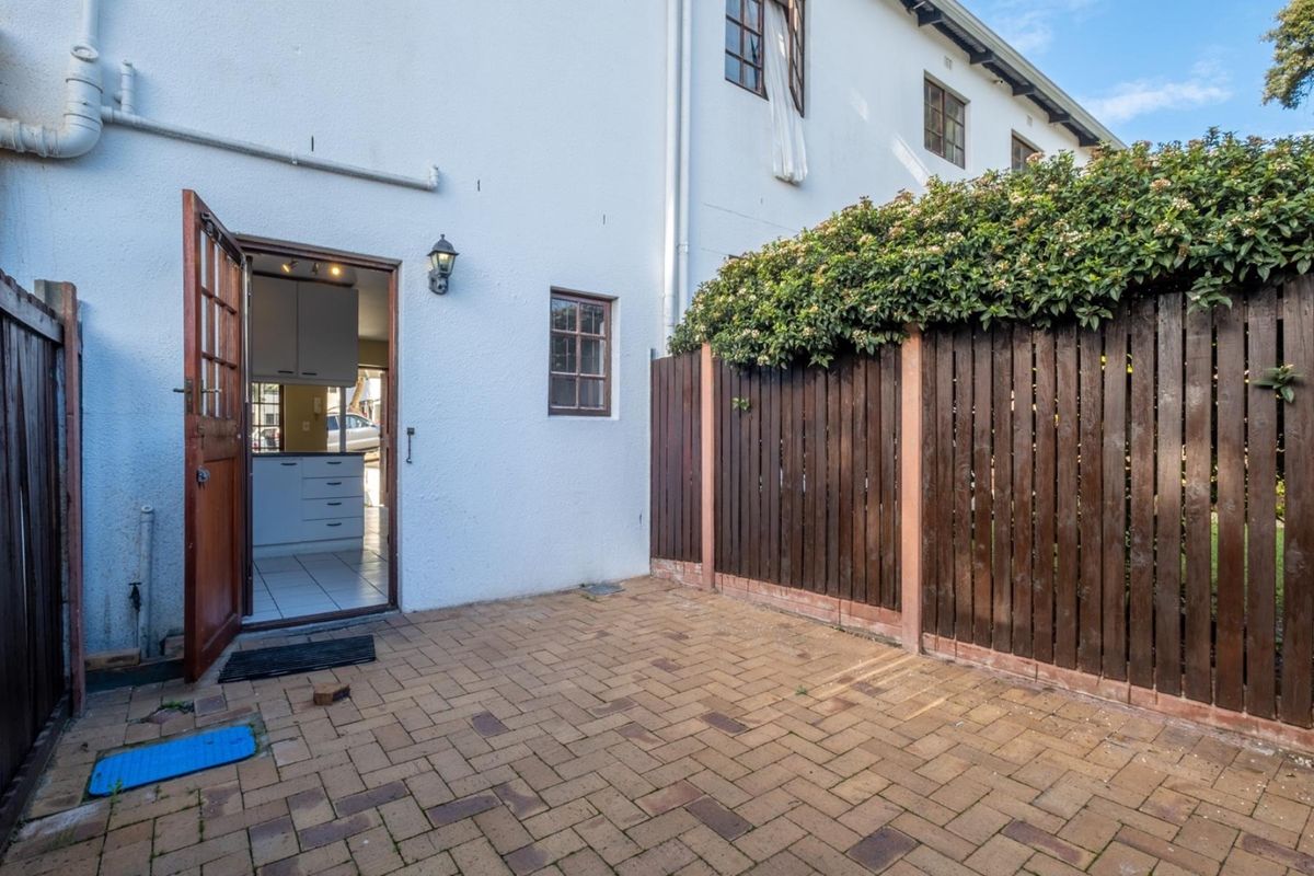 A private rear courtyard featuring paved flooring, a timber boundary fence, and direct access into the kitchen area.