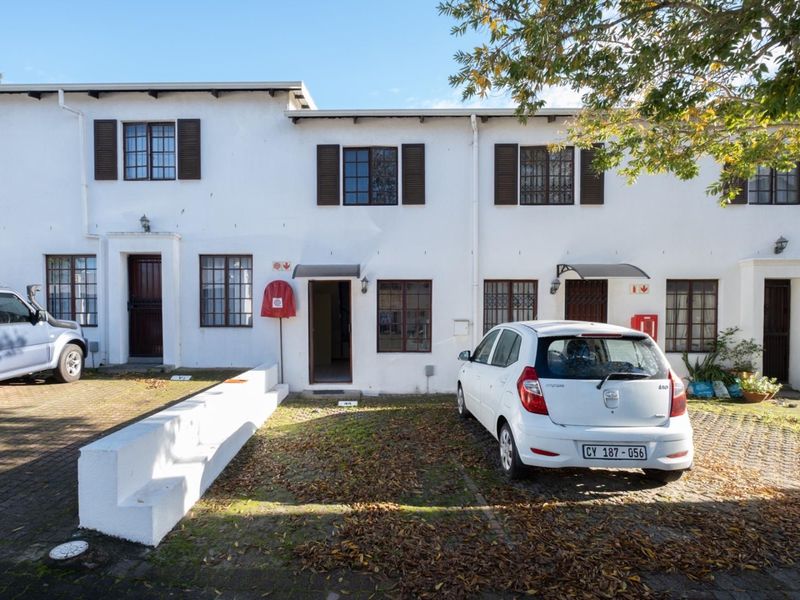 Front elevation of a multi-unit apartment complex featuring paved parking areas, security gates, and traditional window shutters.