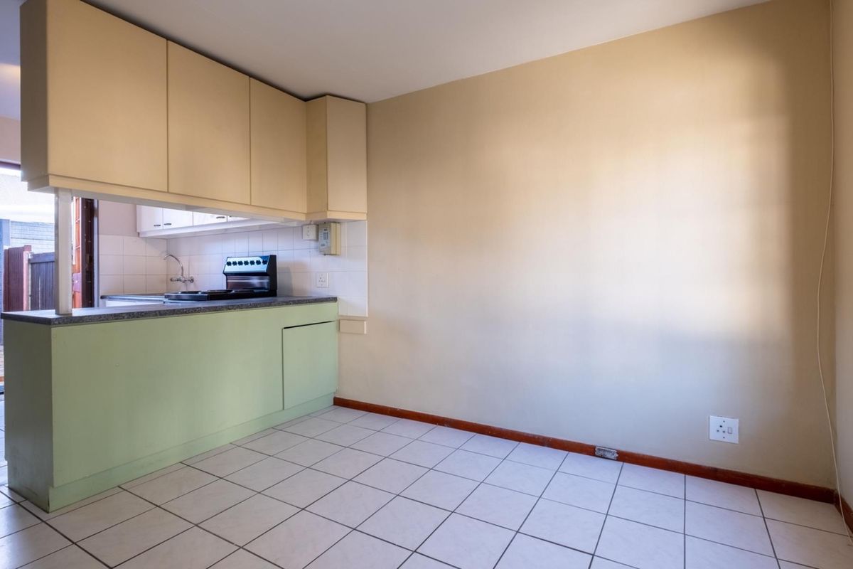 A compact, empty kitchen area featuring tiled flooring, built-in cabinetry, and a functional counter space, offering a blank canvas for potential renovation.