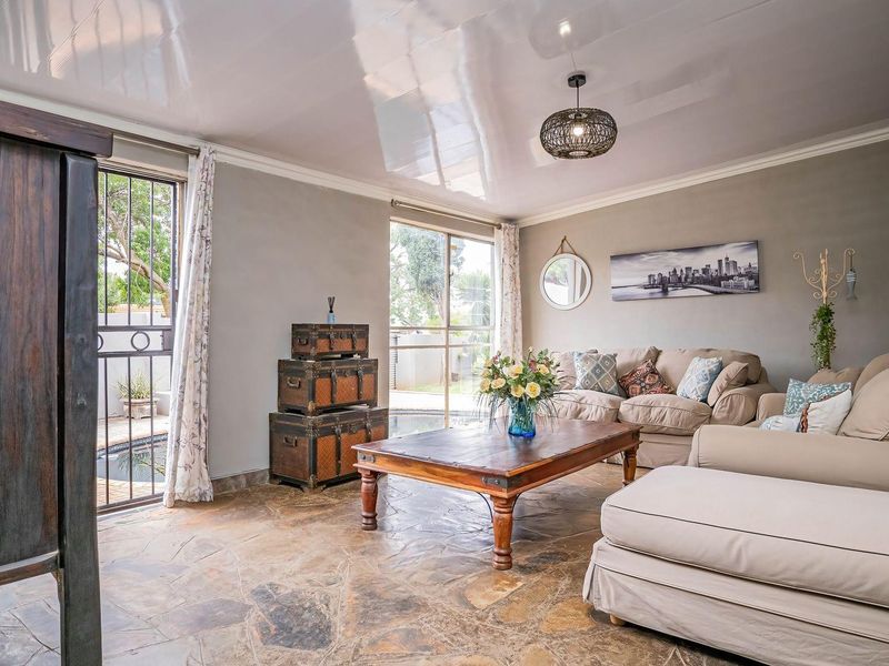 Spacious living room featuring natural stone flooring, a high-gloss ceiling, and direct access to the outdoor pool area through sliding glass doors.