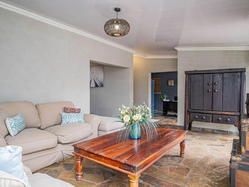 A comfortable living room featuring natural stone flooring, crown molding, and a central pendant light fixture, creating a warm and inviting atmosphere.