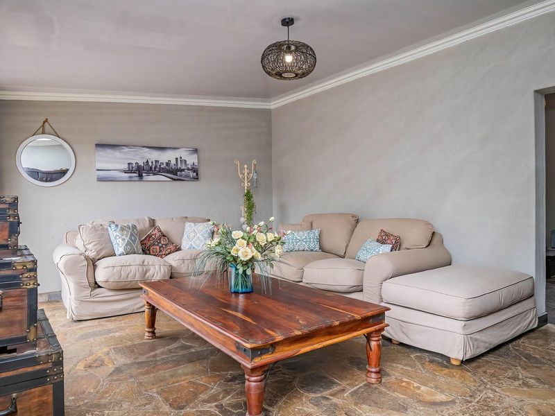 A comfortable living room featuring natural stone tile flooring, crown molding, and a central pendant light fixture.