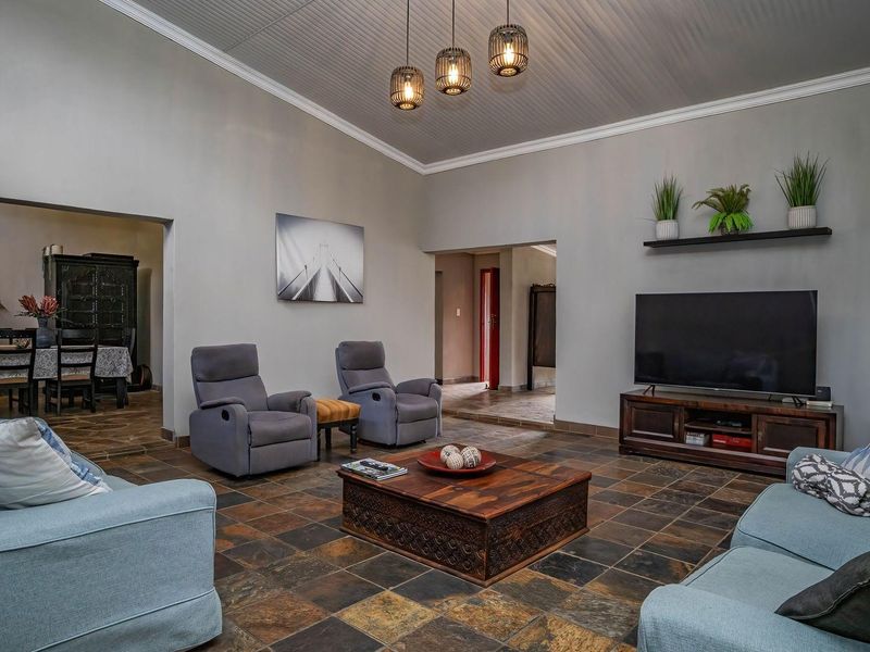 Spacious living room featuring slate tile flooring, high coved ceilings, and pendant lighting, creating a comfortable and inviting atmosphere.