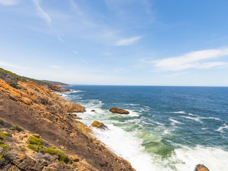 A scenic coastal view showcasing the rugged shoreline, rocky cliffs, and expansive ocean horizon.