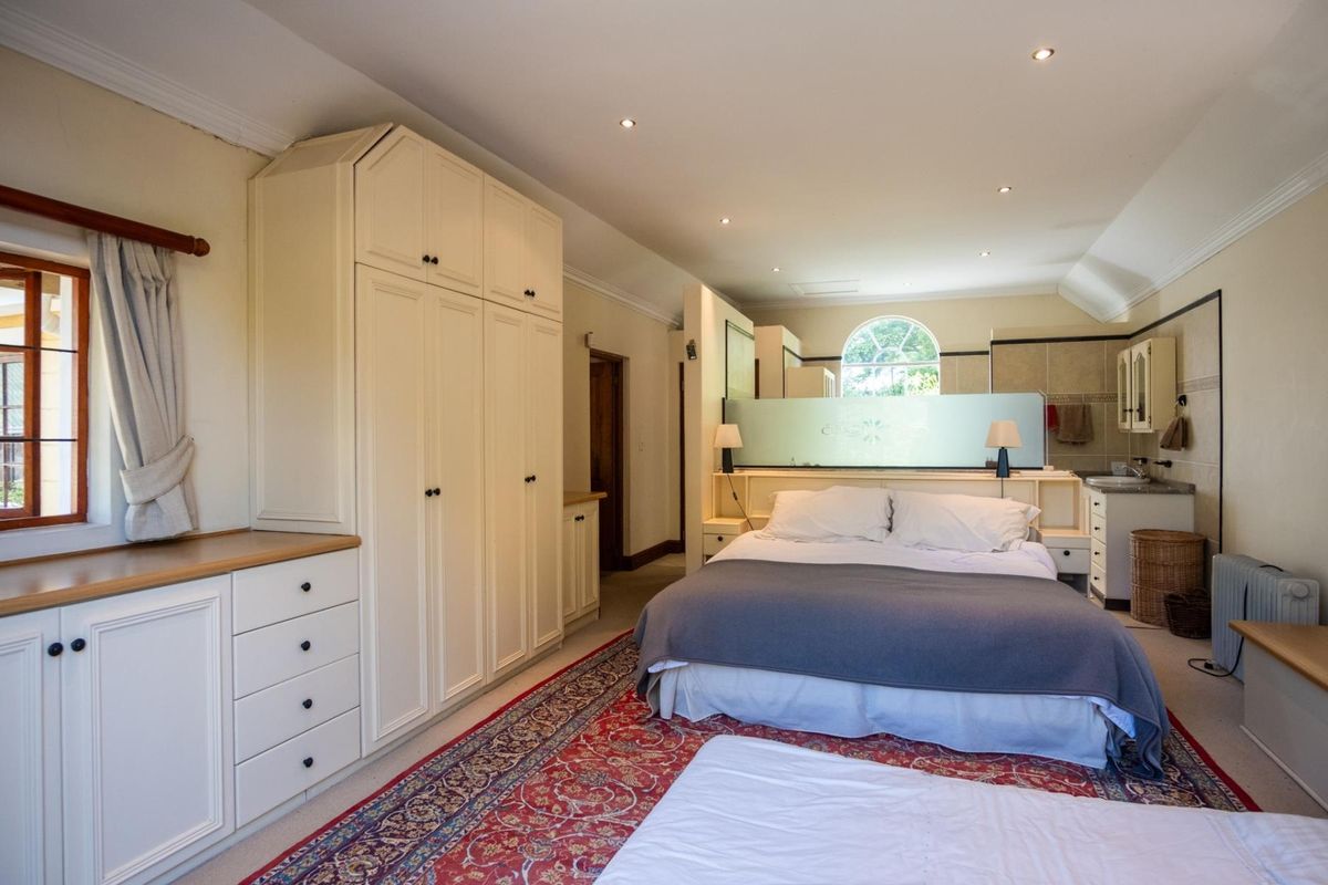 Spacious bedroom featuring extensive built-in cabinetry, a frosted glass partition, and an elegant arched window, creating a bright and functional living space.