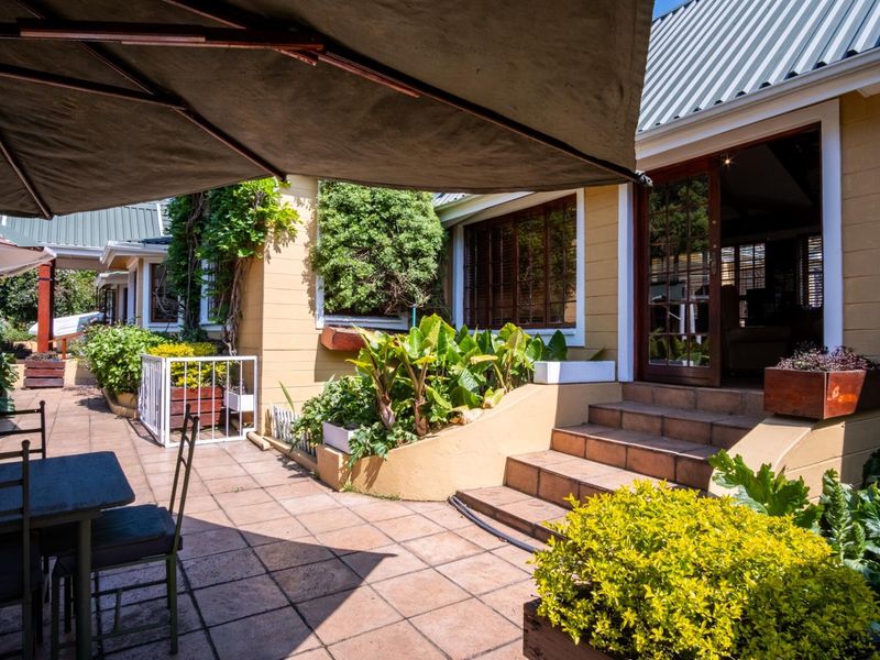 A well-maintained outdoor patio area featuring tiled flooring, masonry steps, and direct access to the interior through timber-framed glass doors.