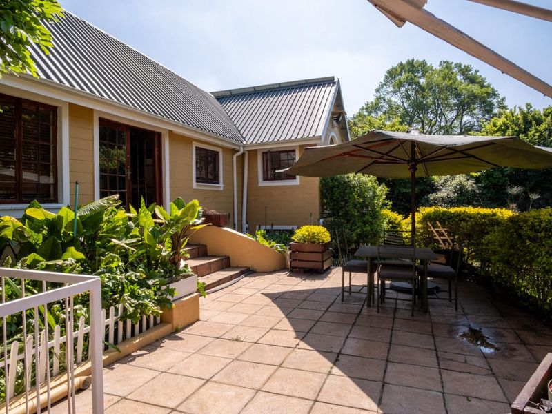 A well-maintained outdoor patio area featuring tiled flooring, direct access to the home via timber-framed doors, and established garden surroundings.