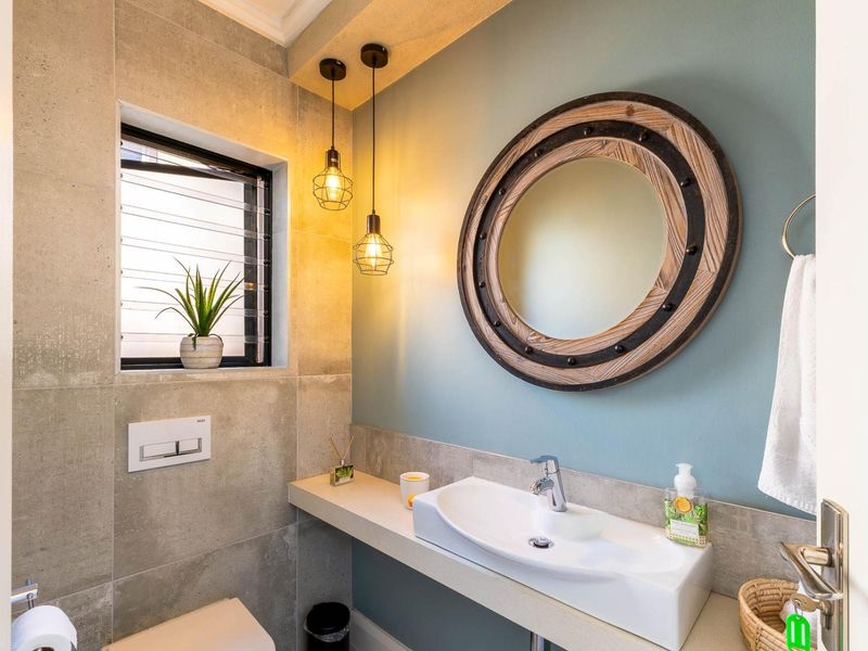 Modern bathroom featuring a floating vanity with a vessel sink, wall-mounted toilet, stylish pendant lighting, and contemporary tiled wall finishes.