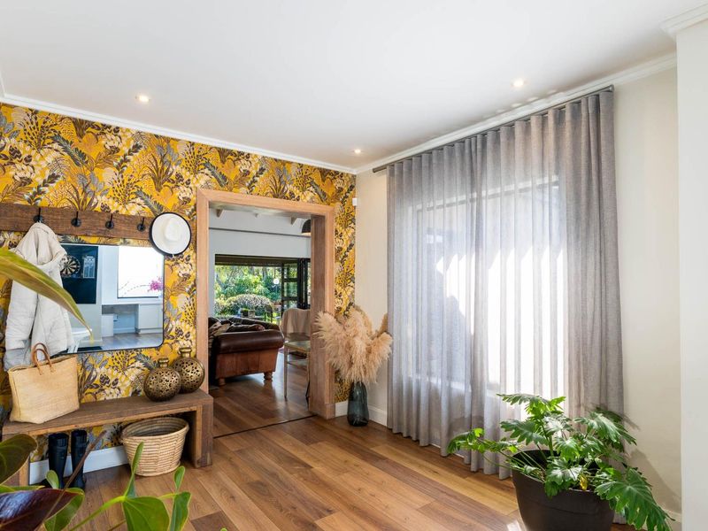 A bright and welcoming entrance hall featuring warm timber flooring, decorative wallpaper, and large windows with elegant floor-to-ceiling curtains.